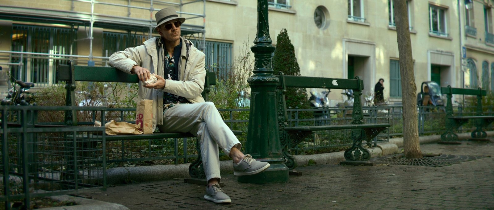 Michael Fassbender sur un banc parisien avec son look de touriste allemand dans The Killer